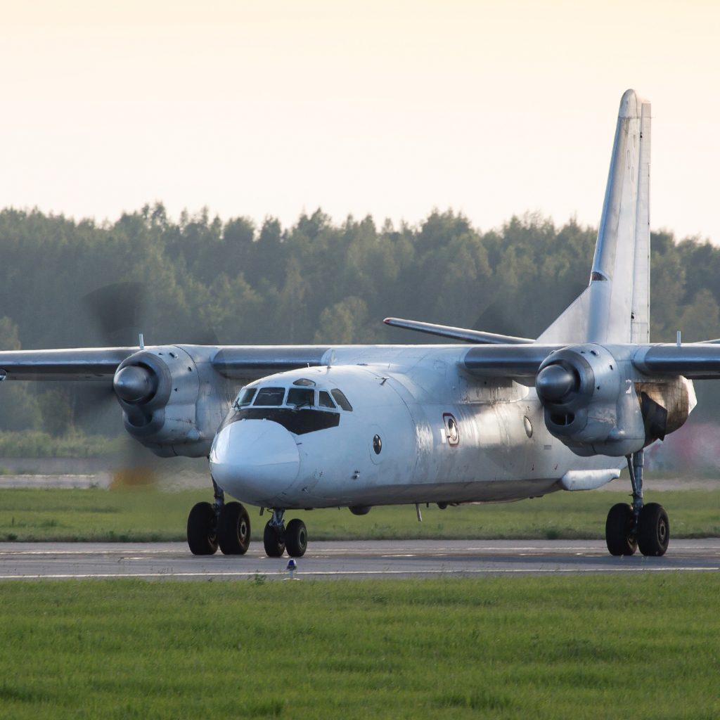 White airplane is taxiing to take off on sunny day, rotating propeller